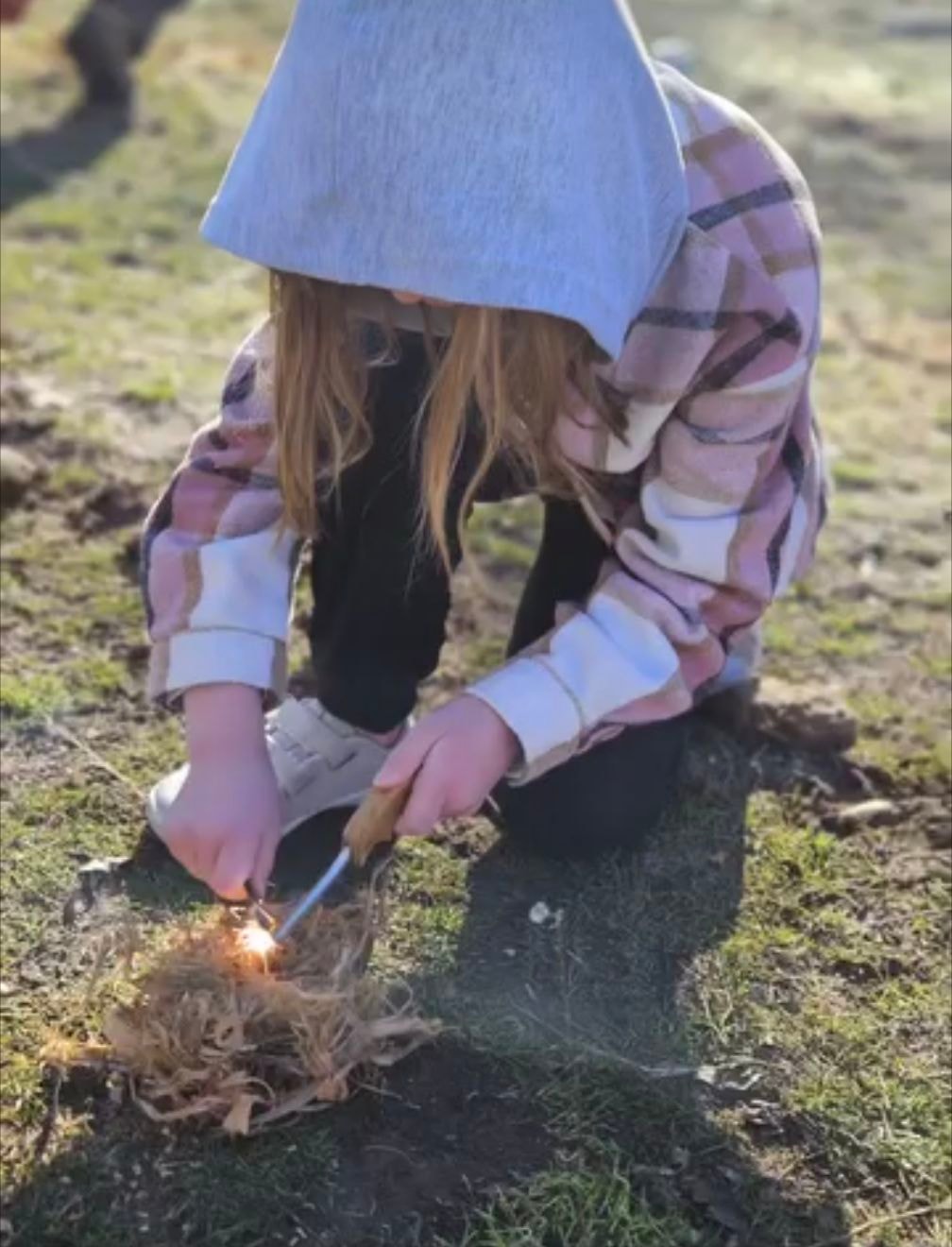 Child striking a ferro rod to start a fire