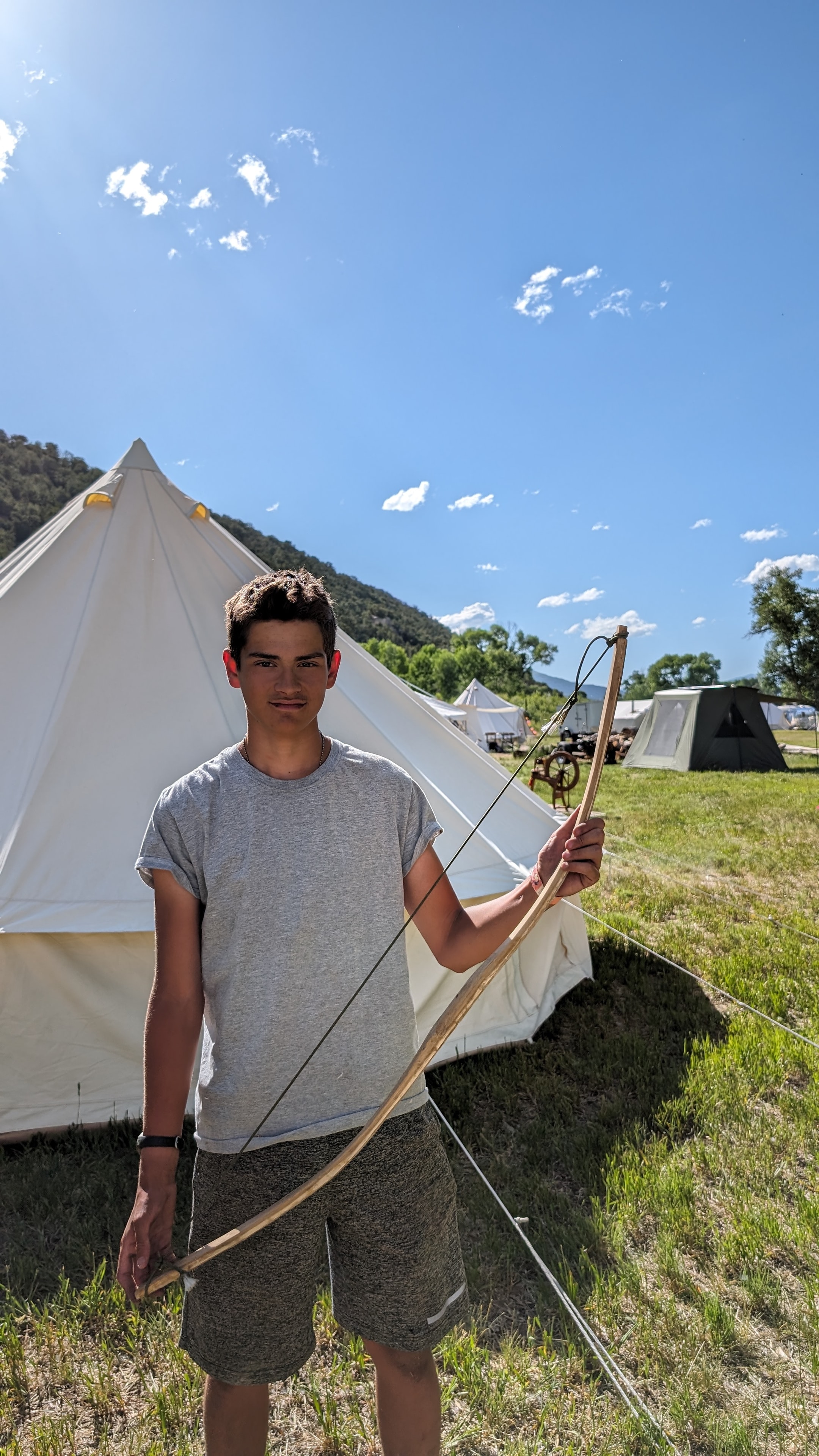 Teen holding a primitive bow at camp