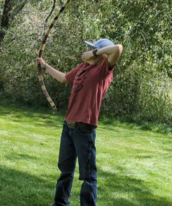 Teen shooting a primitive bow outdoors
