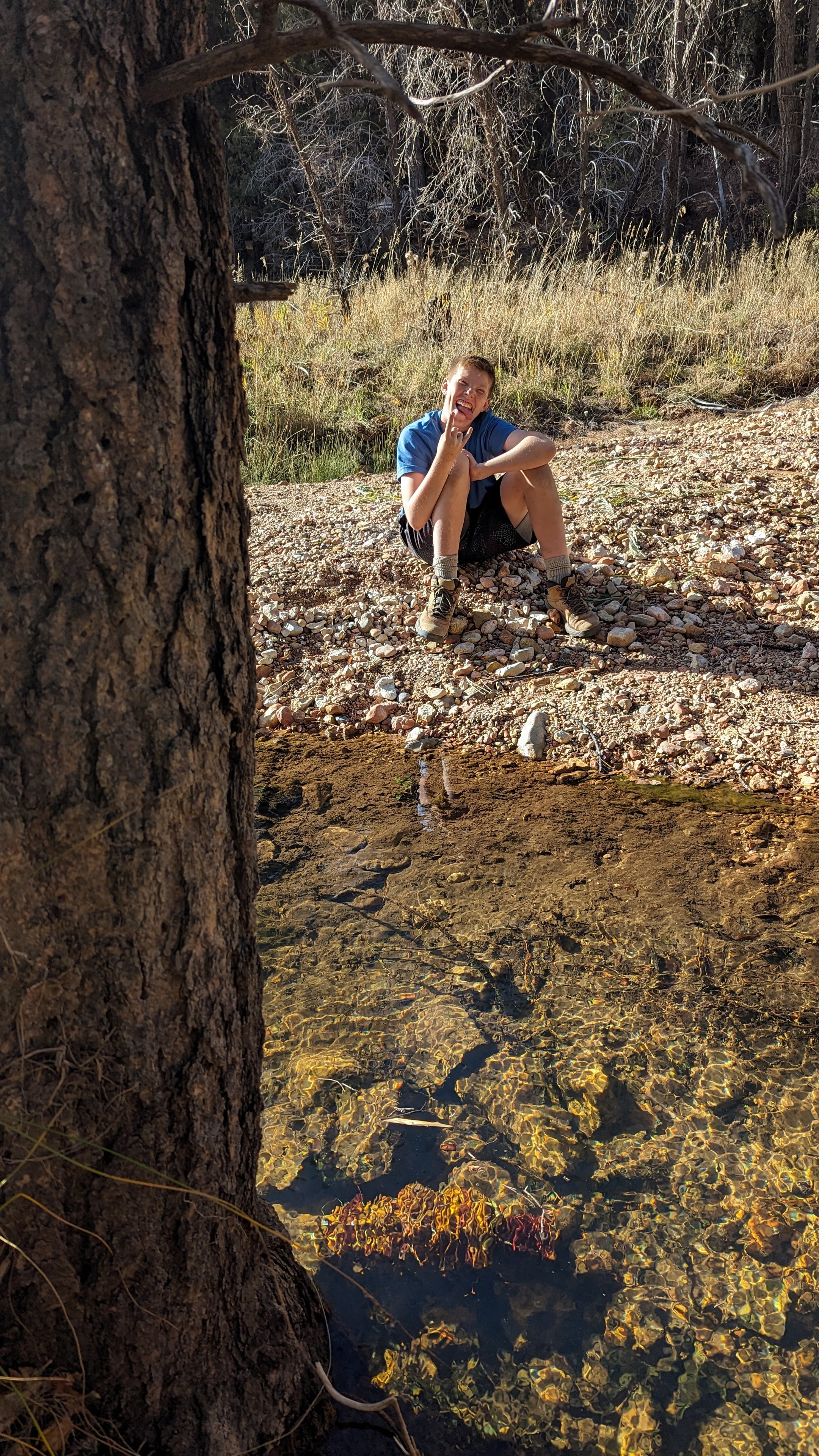 Teen sitting by a clear wilderness stream